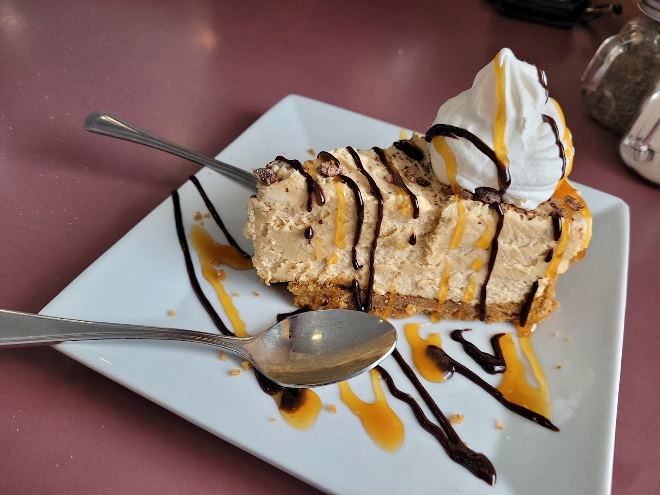 Cheesecake slice with chocolate and caramel drizzle and whipped cream