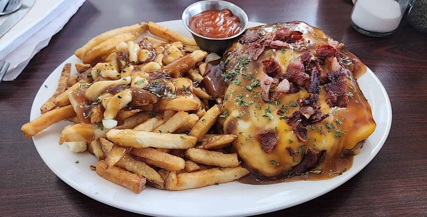 Hot hamburger smothered in gravy with bacon, served alongside poutine fries
