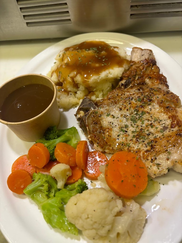 Pork chop with mashed potatoes, gravy, and steamed vegetables