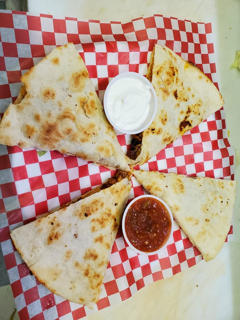 Chicken quesadilla served with salsa and sour cream on classic red-checker paper